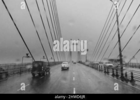 Verschwommenes Bild von Howrah, Westbengalen, Indien. Aufnahme durch Regentropfen, die auf die Windschutzscheibe des Autos fallen, nasses Glas, Verkehr an der Hoogly-Brücke 2.. Stockfoto