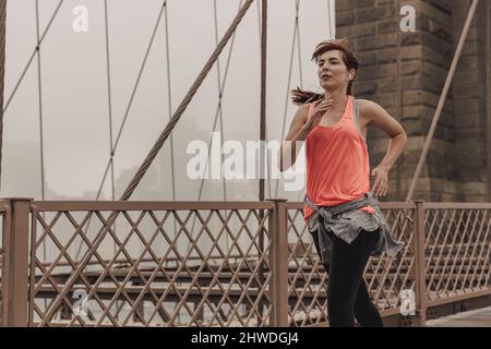 Praktizierende Frau Joggen auf der Brooklyn Bridge Stockfoto