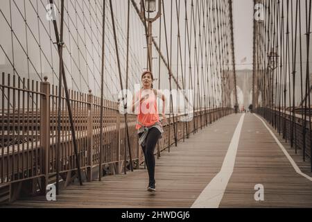 Praktizierende Frau Joggen auf der Brooklyn Bridge Stockfoto