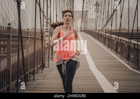 Praktizierende Frau Joggen auf der Brooklyn Bridge Stockfoto