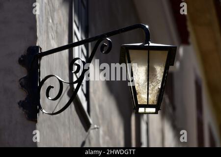 Antike handgefertigte Laterne aus Gusseisen an einer grauen Stuckwand in Nafplio, Griechenland. Stockfoto