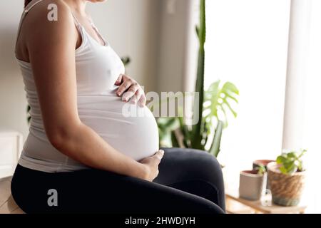 Schwangerin arbeitet zu Hause mit Zuchtübungen. In guter Form bleiben, während Sie auf das Baby warten Stockfoto