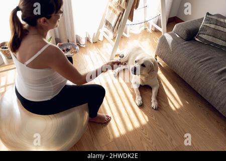 Eine Schwangere, die zu Hause arbeitet, sich ausruhte und gesunde Nahrung in Gesellschaft ihrer besten Freundin isst Stockfoto