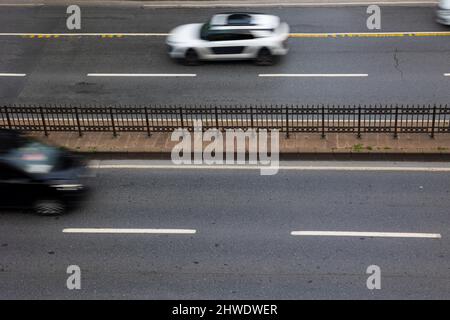 Stadtstraße. Draufsicht auf zweispurige Straße mit bewegungsunscharfen Autos. Verkehr oder Stadtleben Hintergrund. Stockfoto