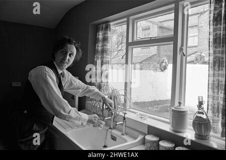 Der Komiker Ken Dodd eröffnet Wohnungen in der Ducie Street und der Beaconsfield Street, Toxteth, Liverpool. Zwei Häuser, eines in jeder Straße, wurden unter einem Team von Schutzhütten- und Planungsexperten zu Wohnungen umgebaut. Ken trinkt eine Tasse Wasser in der neuen Küche von Mrs Mrgaret Gibbs in der Ducie Street. 7.. April 1970. Stockfoto