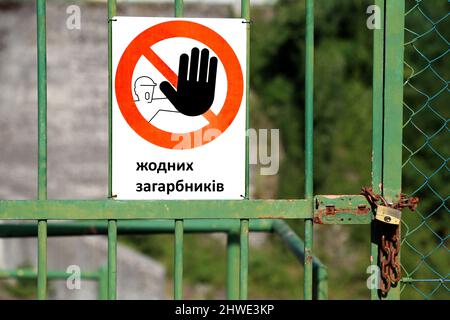 Rotes Schild mit großer schwarzer Hand, die auf einen Stopp hinweist, und eine großartige Botschaft „No Invaders“ in ukrainischer Sprache auf einem Tor, das mit einem Vorhängeschloss geschlossen ist Stockfoto