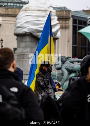 London, Großbritannien. 05. März 2022. Bei einer Friedensdemonstration gegen die russische Invasion in der Ukraine hält ein schwarz gekleideter Mann eine ukrainische Flagge über seinem Kopf. © Matt Goodrum/Alamy Live News Stockfoto
