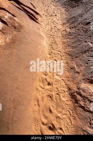 Blick auf Narrow Path Between Large Rocks mit Schuhdrucken auf dem Sand Stockfoto