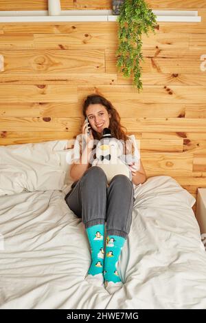 Junge Frau mit Handy im Bett Stockfoto