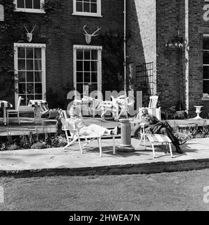 Johnnie und Fanny Cradock, die Kochexpertin im Fernsehen, sind in ein neues Zuhause in der Nähe von Watford, Hertfordshire, gezogen. Das Haus selbst war ursprünglich ein Ferienhaus aus dem 18.. Jahrhundert, das im Laufe der Jahre darauf gebaut wurde, wobei die ursprüngliche Fassade so nahe wie möglich gehalten wurde. Das Interieur wurde komplett von den Cradock's mit allen üblichen modernen Annehmlichkeiten ausgestattet, einschließlich einer großen Küche mit sechs Gasherden, in der sie ein kleines Team von jungen Leuten anweisen, die ihnen bei ihren Fernsehsendungen helfen. Fanny und Johnnie beim Entspannen im Garten. 9.. Juni 1969. Stockfoto