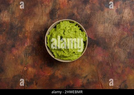 Schüssel mit frisch zubereiteter frischer Guacamole auf einem Holzhintergrund in Brauntönen. Gesunde Lebensmittel, die reich an Omega-3-Fetten sind, die helfen, Cholesterin zu verhindern. Super Stockfoto