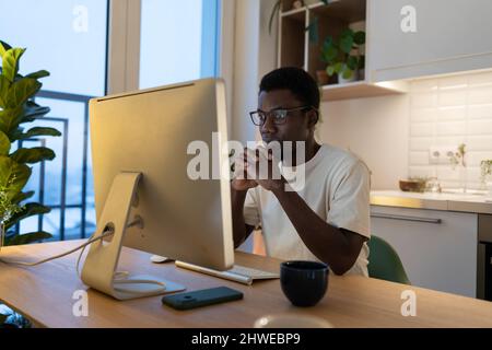 Konzentrierter Softwareentwickler, der von zu Hause aus an der Programmierung von Anwendungen arbeitet, konzentrierte sich auf den Computerbildschirm Stockfoto