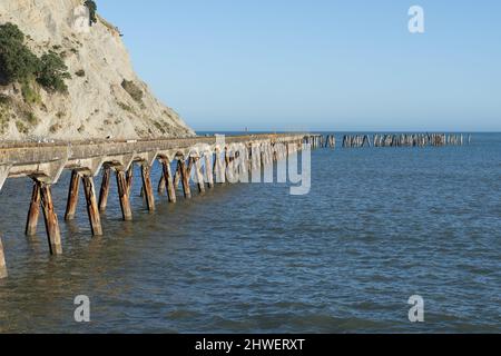 Der lange verlassene historische Kai von Tokomaru Bay erstreckt sich bis zur Bucht, Ostküste, Neuseeland. Stockfoto