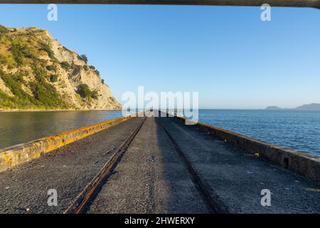 Linien der Rand- und Mittelbahn, die zum Ende des alten Tokomaru Bay Wharf führen. Stockfoto