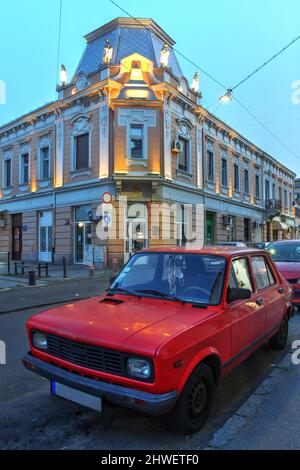 Ein wunderschön erhaltener legendärer Yugo parkte in der Dämmerung vor historischen Gebäuden in Zemun, Belgrad, Serbien. Stockfoto