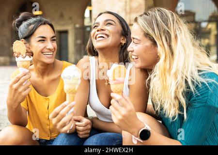 Drei fröhliche Frauen essen Eis während der Sommerferien in Italien Stockfoto
