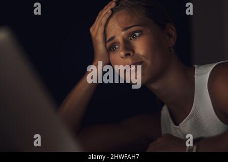 Stress entsteht, wenn du gegen dich selbst arbeitest. Aufnahme einer jungen Geschäftsfrau, die während einer späten Nacht auf der Arbeit besorgt aussieht, während sie einen Laptop benutzt Stockfoto