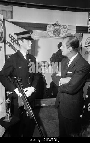 Prinz Philip, Herzog von Edinburgh, abgebildet während eines Besuchs in Birmingham, bei einer Jugendausstellung in Lewis' Kaufhaus. Birmingham, West Midlands. Der Herzog hält inne, um mit dem Polizeikadetten Michael Walker von Sparkbrook, dem britischen Champion-Kadett beim Zielschießen, zu sprechen, der mit seiner Trophäe und dem Gewehr, mit dem er sie gewonnen hat, gesehen wird. 12.. November 1970. Stockfoto