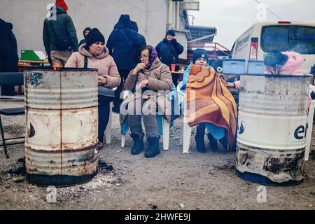 Medyka, Karpatenland, Polen. 3. März 2022. Ukrainische Flüchtlinge wärmen sich mit provisorischen Heizungen auf.Polnisch-ukrainischer Grenzübergang in Medyka. Seit Beginn der russischen Invasion in der Ukraine sind rund 700.000 Menschen nach Polen geflohen, um dem Krieg zu entkommen. Trotz erheblicher Fehlinformationen und isolierter Vorfälle werden ukrainische Flüchtlinge mit Empathie, Hilfe und Verständnis begrüßt, aber viele humanitäre Experten deuten darauf hin, dass bei einem so großen Zustrom von Menschen in wenigen Wochen eine Krise eintreten könnte. (Bild: © Filip Radwanski/SOPA Images via ZUMA Press Wire) Stockfoto