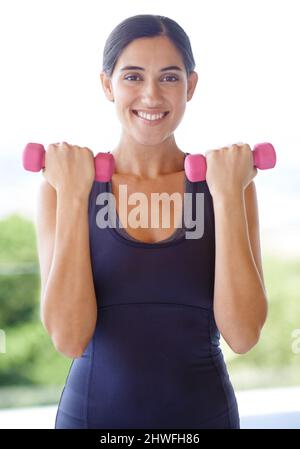 Fitness wartet auf niemanden. Porträt einer jungen Frau, die Gewichte nach draußen hebt. Stockfoto