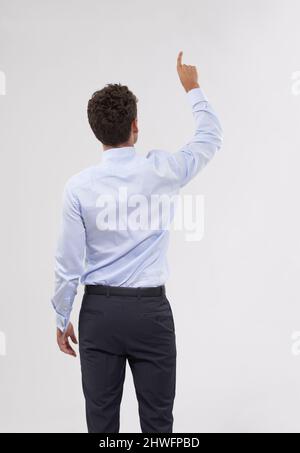 Auswahl der besten Option. Rückansicht eines hübschen jungen Geschäftsmannes, der eine transparente digitale Schnittstelle berührt. Stockfoto