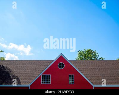 Rotes Giebel Dach des großen Hauses mit weißem Holz gerahmt und dekoriert mit runden und quadratischen Fenster auf blauem Himmel Hintergrund mit Kopierraum. Stockfoto