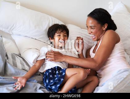 Meine kleine Bohne wächst so schnell auf. Aufnahme einer schönen jungen Mutter, die sich zu Hause im Bett mit ihrem Sohn entspannt. Stockfoto