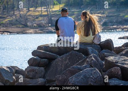 Paare unterhalten sich auf den Küstenfelsen auf Waveshaper Island im Chattahoochee River entlang des Columbus Riverwalk in Uptown Columbus, Georgia. Stockfoto