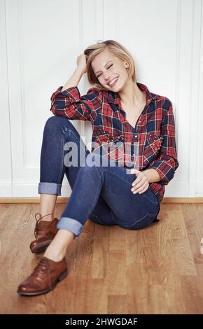 Nichts kann schief gehen, wenn ich meine Brogues an habe. Ein Porträt einer schönen jungen Frau, die zu Hause auf einem Holzboden sitzt. Stockfoto