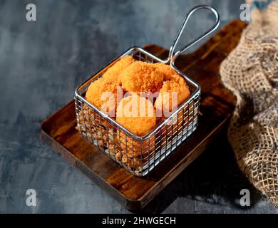 Golden Scallops in einer tiefen Fritteuse auf Holzbrett Seitenansicht auf dunklem Hintergrund Stockfoto