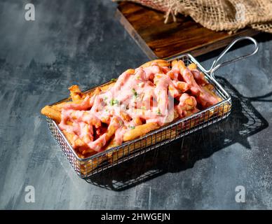 Frittierte Mentaiko-Pommes Frites in einer Fritteuse Seitenansicht auf dunklem Hintergrund Stockfoto
