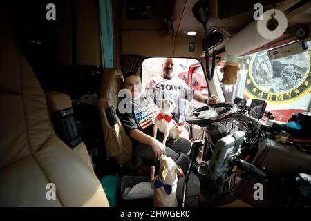 Hagerstown, USA. 05. März 2022. Ein Mann und eine Frau posieren während des „Peoples Convoy“ im Taxi ihres LKWs, während er am 5. März 2022 in Hagerstown, Maryland, USA, für einen zweiten Tag auf dem Hagerstown Speedway pausiert. Der Konvoi, inspiriert von den kanadischen Truckern, einschließlich des Ottawa-Protests, bewegt sich entlang Maryland I70 in Richtung der Hauptstadt der Nationen, bevor er auf dem Hagerstown Speedway für zwei Tage der Organisation und Neugruppierung Halt macht.die Trucker fordern das Ende aller COVID-19-Mandate. Quelle: SIPA USA/Alamy Live News Stockfoto