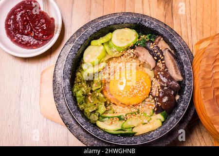 Bibimbap in einer schwarzen, beheizten Steinschüssel, koreanisches traditionelles Gericht - Bibimbap gemischter Reis mit Gemüse umfassen Rindfleisch und Spiegelei, japanisches Hot Pot Essen Stockfoto