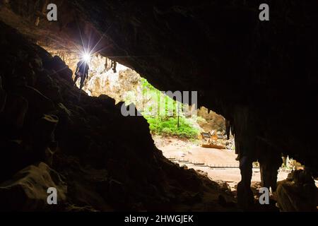 Der junge Entdecker erkundet die geheimnisvolle Höhle mit einer Fackel, Phraya Nakhon Cave, Thailand. Stockfoto