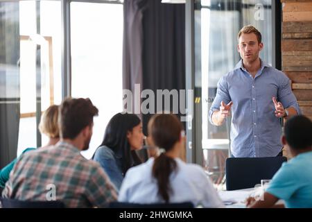 HES hat einige großartige Marketing-Erkenntnisse gewonnen. Aufnahme eines männlichen Designers, der seine Ideen in einem Meeting seinem Team vorstellt. Stockfoto