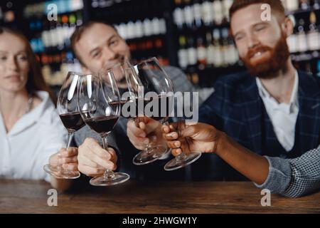 Konzept multikulturelle Freundschaft, Nahehäufte afrikanischer Frauen und europäischer Männer werden im Restaurant mit Gläsern Rotwein überprüft. Stockfoto