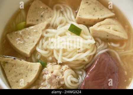 Vietnamesische Reisnudeln oder Pho mit Wurst in Scheiben schneiden und Schweinefleisch in einer Suppe auf einer Schüssel hacken Stockfoto