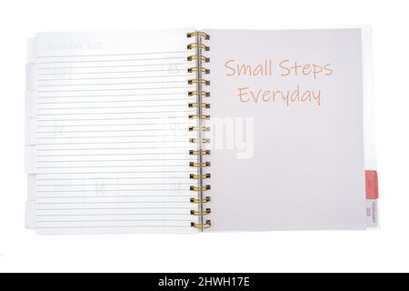 Notizbuch mit der Aufschrift KLEINE SCHRITTE JEDEN TAG auf weißem Hintergrund Stockfoto