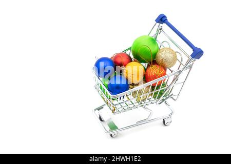 Einkaufskarte oder Supermarktwagen mit Weihnachtsbaumkugeln auf weißem Hintergrund Stockfoto