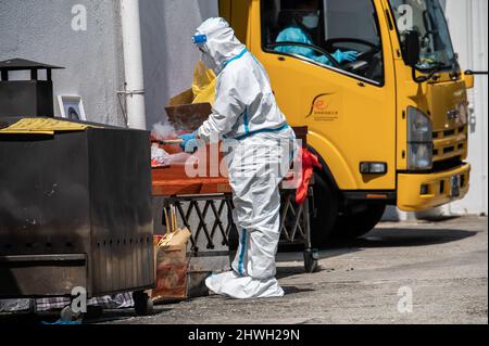Ein privater Mitarbeiter in der Leichenhalle von PPE bereitet den Leichnam eines Covid-19-Opfers auf die Beerdigung in der öffentlichen Leichenhalle von Victoria vor. Mit dem jüngsten Anstieg der Todesfälle aufgrund des Omicron-Ausbruchs in Hongkong sind die örtlichen Leichenhallen in der Lage, und die Regierung verlässt sich auf Krankenhäuser und private Leichenhäuser, um Hilfe zu erhalten. Am 5. März 2022 sind in der letzten Welle 1561 Menschen gestorben, was die Gesamtzahl der bekannten COVID-19-Todesfälle in Hongkong auf 1774 brachte. Die meisten Todesfälle wurden bei älteren Menschen verzeichnet, von denen viele entweder nicht oder nicht vollständig geimpft waren. (Foto von Ben Marans/SOPA Images/Sipa USA) Stockfoto