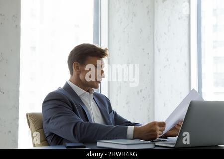 Fokussierter qualifizierter Geschäftsmann im mittleren Alter von 40s Jahren, der das Dokument liest. Stockfoto