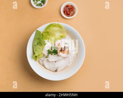 singapore Food Fish Bee Hoon in Scheiben geschnitten in einer Schüssel mit Suppe, Chilisauce und Frühlingszwiebeln Draufsicht auf Holztisch Stockfoto