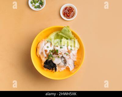Thai-Essen Fischbrei in Scheiben geschnitten in einer Schüssel mit Suppe, Chilisauce und Frühlingszwiebeln Draufsicht auf Holztisch Stockfoto