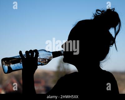 Rottweil, Deutschland. 04. März 2022. Illustration: Ein Teenager-Mädchen trinkt in ihrem Zimmer eine Flasche Wodka. (To dpa 'DAK: Depressive Kinder missbrauchen besonders oft Suchtstoffe'). Kredit: Silas Stein/dpa/Alamy Live Nachrichten Stockfoto