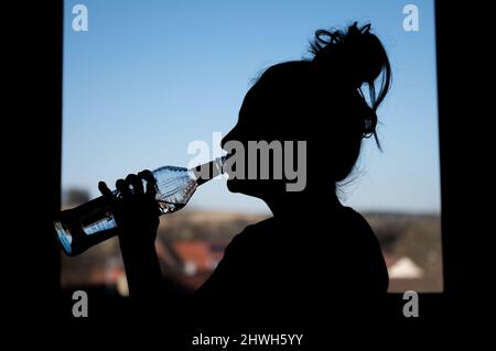 Rottweil, Deutschland. 04. März 2022. Illustration: Ein Teenager-Mädchen trinkt in ihrem Zimmer eine Flasche Wodka (Re dpa 'DAK: Depressive Kinder missbrauchen besonders oft Suchtstoffe'). Kredit: Silas Stein/dpa/Alamy Live Nachrichten Stockfoto