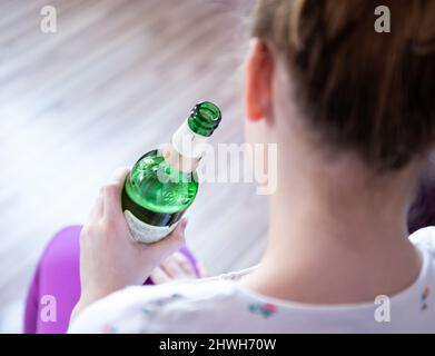 Rottweil, Deutschland. 04. März 2022. Abbildung: Ein Teenager-Mädchen hält eine Flasche Bier in ihrem Zimmer. (To dpa 'DAK: Depressive Kinder missbrauchen besonders oft Suchtstoffe'). Kredit: Silas Stein/dpa/Alamy Live Nachrichten Stockfoto