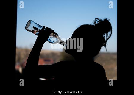 Rottweil, Deutschland. 04. März 2022. Illustration: Ein Teenager-Mädchen trinkt in ihrem Zimmer eine Flasche Wodka. (To dpa 'DAK: Depressive Kinder missbrauchen besonders oft Suchtstoffe'). Kredit: Silas Stein/dpa/Alamy Live Nachrichten Stockfoto