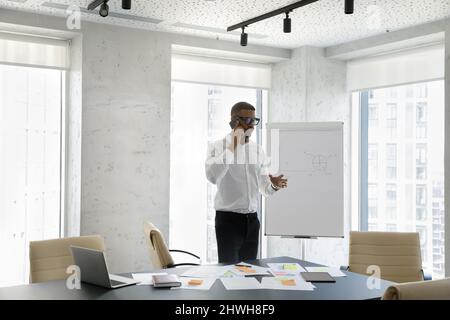 Fokussierter junger afroamerikanischer Geschäftsmann, der Telefongespräche führt. Stockfoto