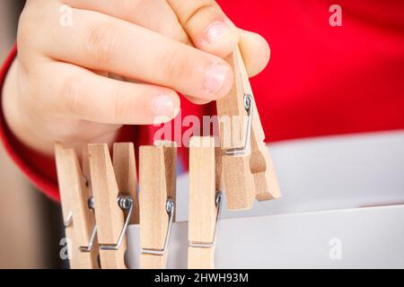 Vorschulkinder spielen mit Holzclip. Entwicklung von motorischen Fähigkeiten, Koordination, Kreativität und logischem Denken der Kinder Stockfoto