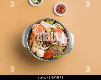 Mala Xiao Wan in einer Schüssel mit Chilisauce und Pulver und Frühlingszwiebeln Draufsicht auf Holztisch Stockfoto